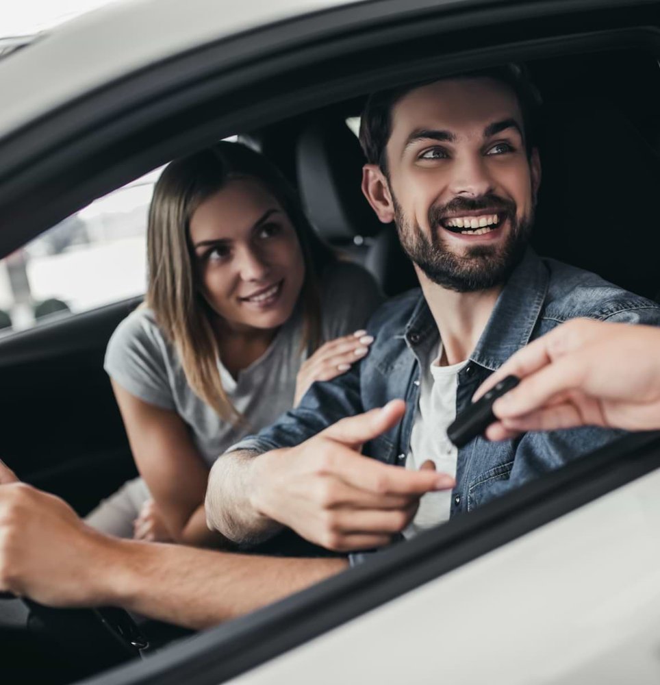 Happy young couple smile and take keys to their new car