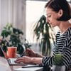 A woman drinking a cup of coffee enters her credit card info online