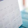 Desktop calendar stands upright on a blue table.