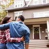 Couple embracing in front of beige house