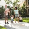 Young family walking on sidewalk in residential neighbourhood after a day of downtown shopping