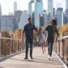 Family walking together on bridge with cityscape in the background