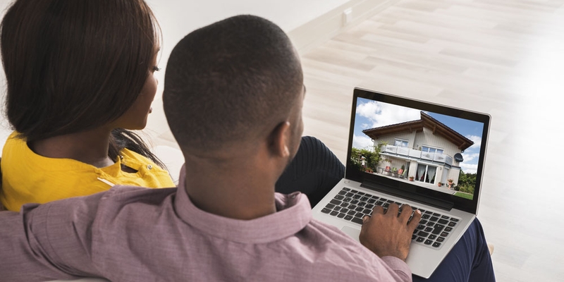 A couple browse house listings on a laptop