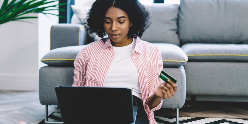 A woman purchases something on her laptop via credit card in her modern living room