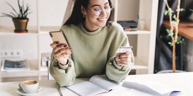 A young woman buying something on her phone with her credit card