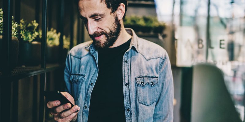 Man in denim jacket on his mobile phone somewhere downtown