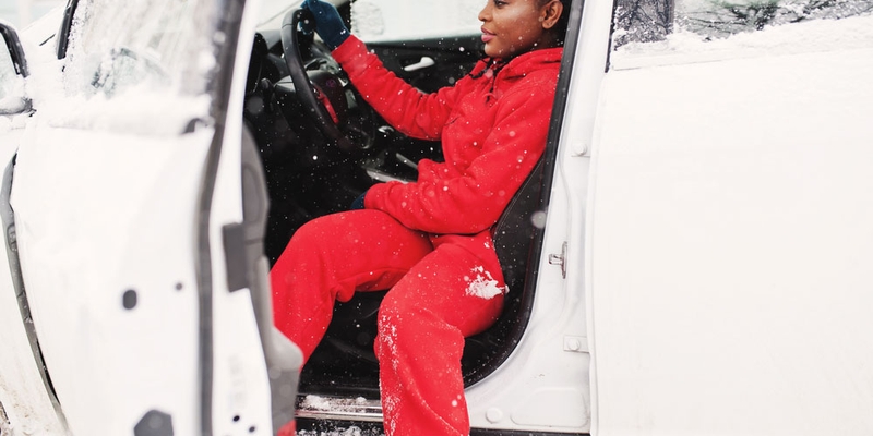 A woman gets out of her vehicle in the winter wearing a sweatsuit