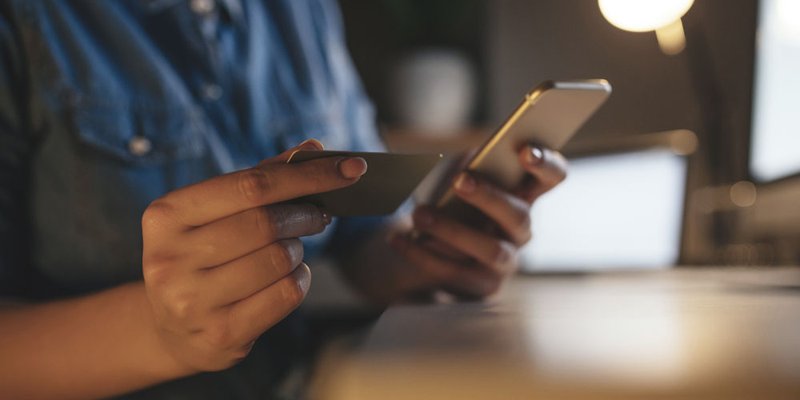 Closeup of a person typing their credit card number into their mobile phone