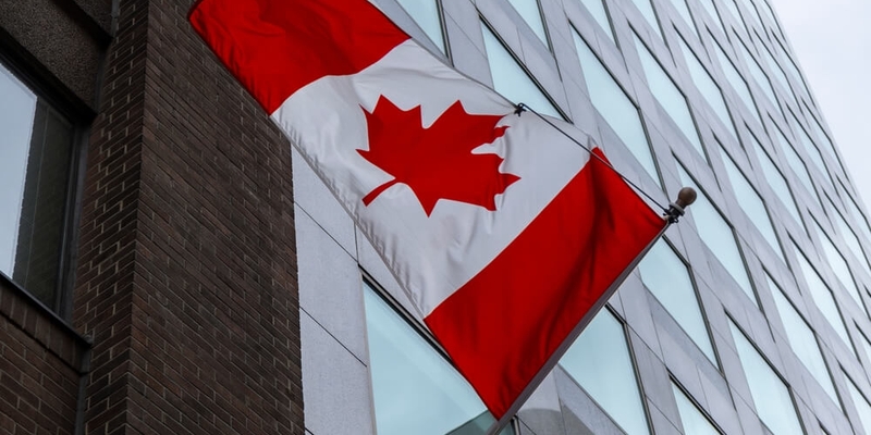 canadian flag waving outside bank of canada_BOC lowers key interest rate