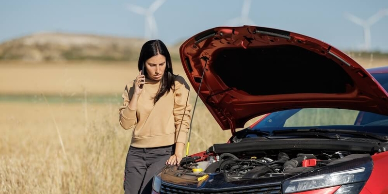 distressed woman with a broken down car calling emergency roadside assistance