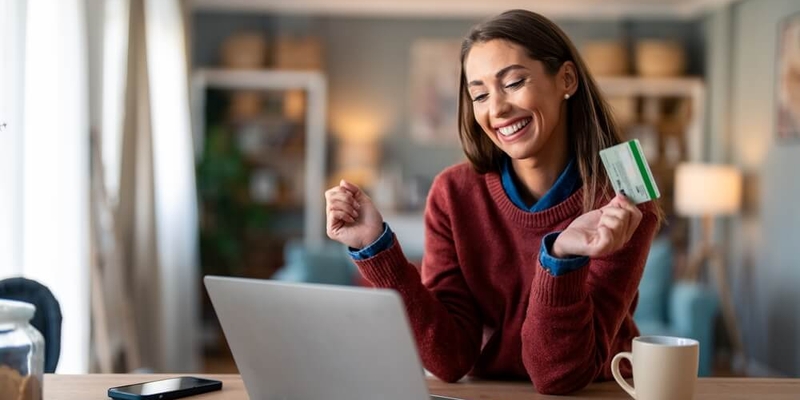 girl in swetaer looking at laptop with creidt card in hand (1)