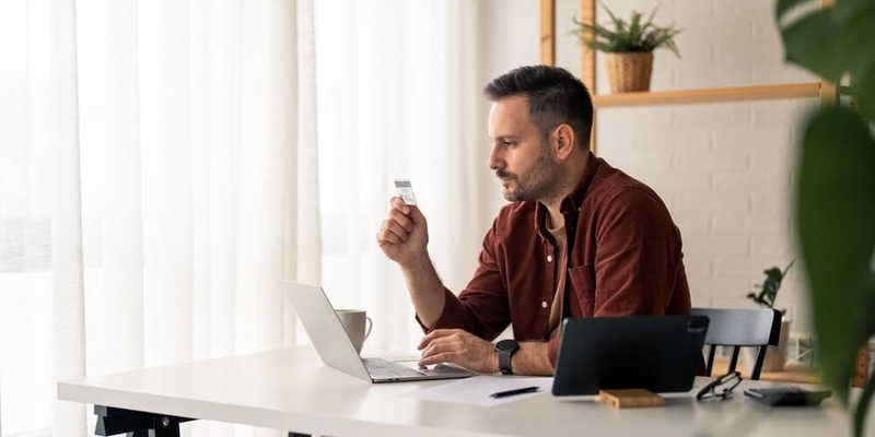 pensive looking freelancer staring intensely at his credit card_Should you accept that pre-approved credit limit (1)