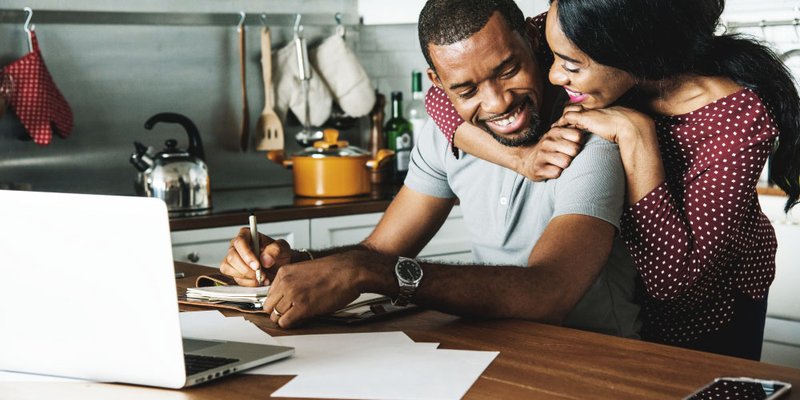 happy loving couple working on their laptop in the kitchen