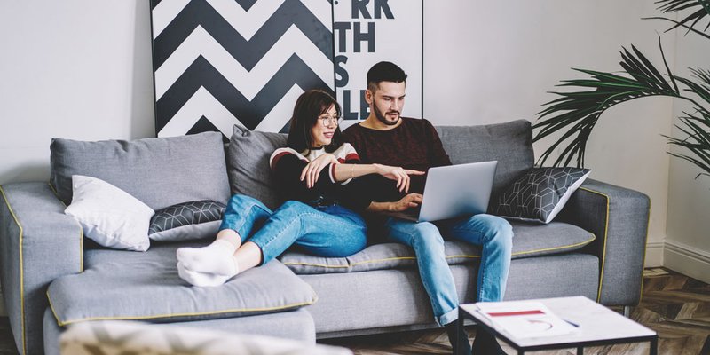 Couple in modern living room looking at laptop