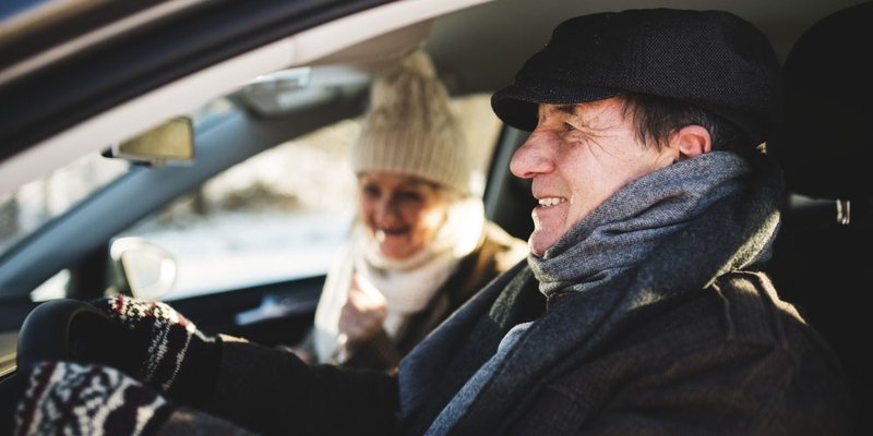 Senior couple in car dressed in fashionable, modern winter gear