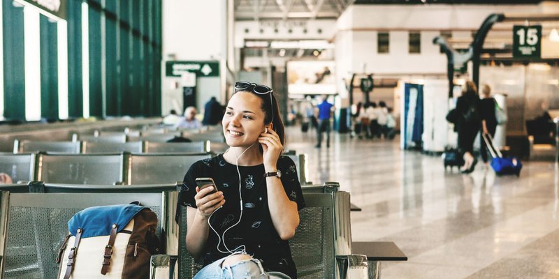Woman listens to music while waiting for her flight at airport