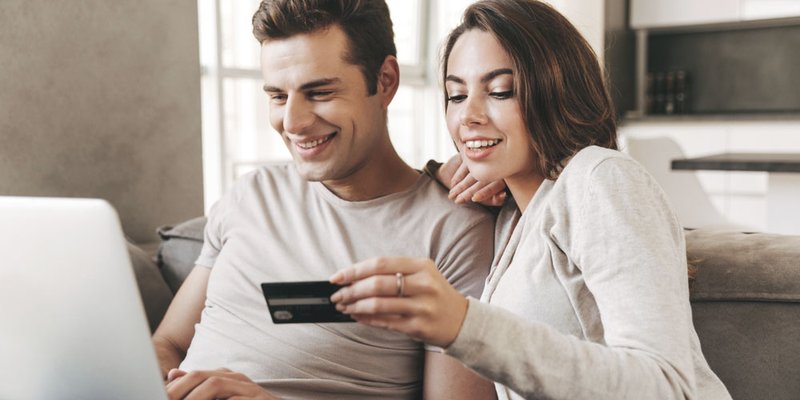 A woman reads out her credit card details as a man types the information into a laptop