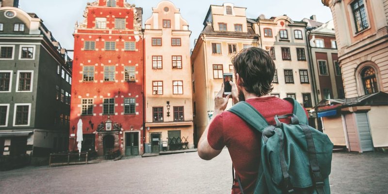 A man takes a picture of the colourful houses on the street