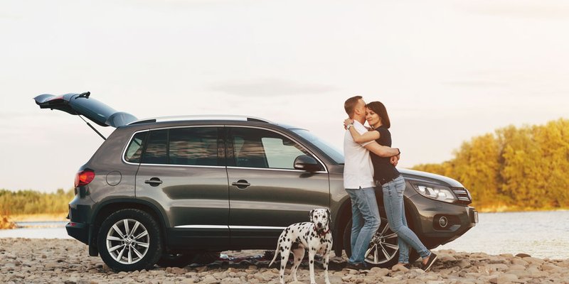 A couple and their dog stop by a river on a road trip