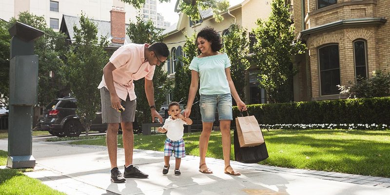 Young family walking on sidewalk in residential neighbourhood after a day of downtown shopping