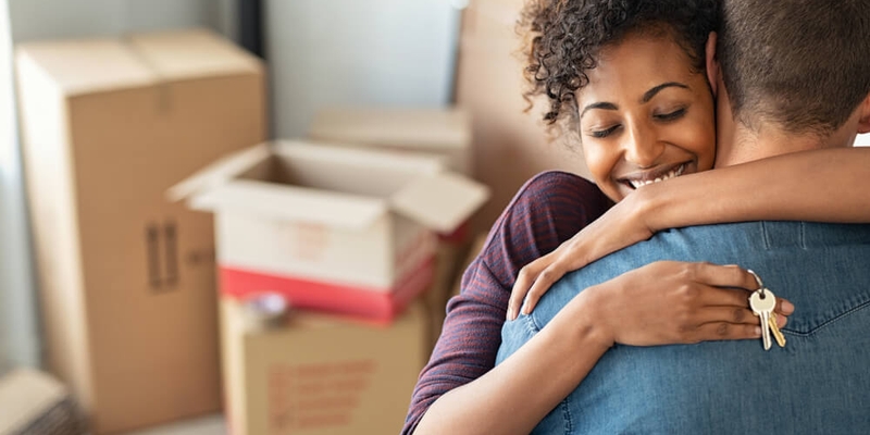 young couple moving into their new home stack of boxes behind them_closing costs for sellers